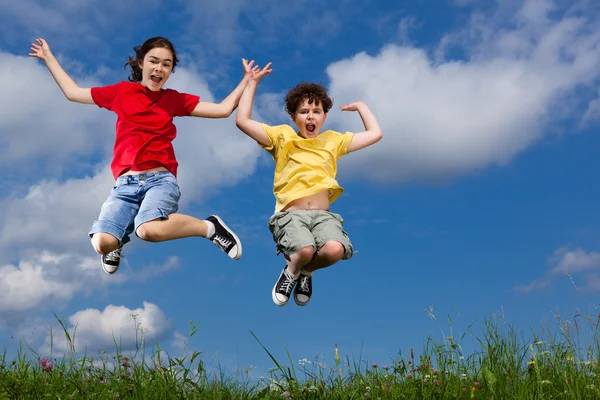 Girl and boy jumping outdoor — Stock Photo, Image