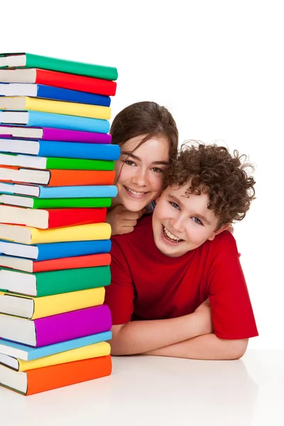 Дети за стопкой книг — стоковое фото