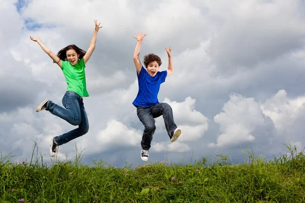 Menina e menino pulando — Fotografia de Stock