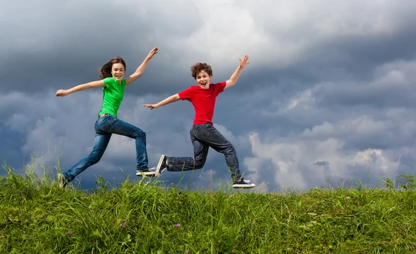 Ragazza e ragazzo salto — Foto Stock