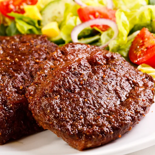 Grilled steaks and vegetable salad — Stock Photo, Image