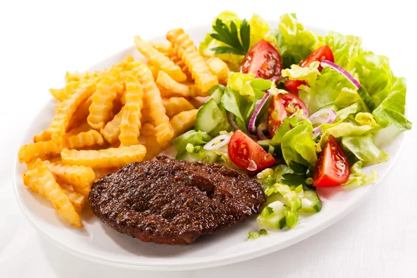 Grilled steaks, French fries and vegetable salad — Stock Photo, Image