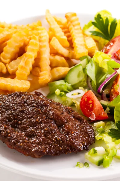 Grilled steaks, French fries and vegetable salad — Stock Photo, Image