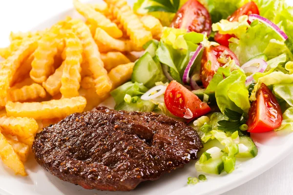 Gegrilde steaks, Franse frietjes en plantaardige salade — Stockfoto