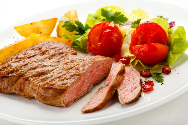 Steaks grillés, pommes de terre cuites au four et salade de légumes — Photo