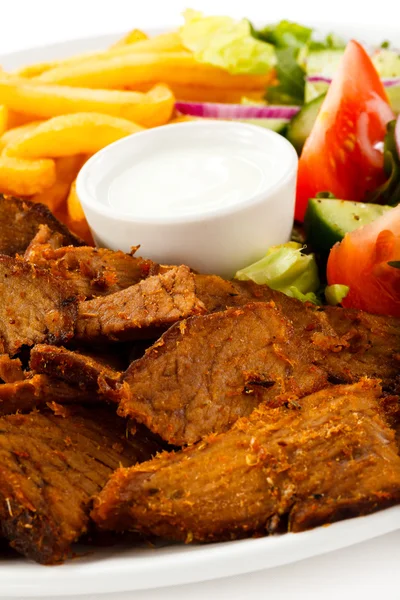 Мясо на гриле с жареной картошкой и овощным салатом — стоковое фото