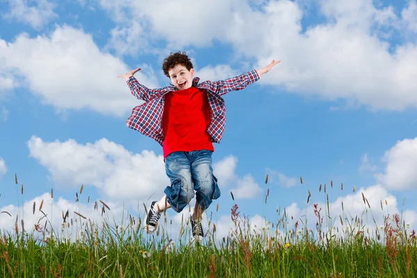 Junge springt gegen blauen Himmel — Stockfoto