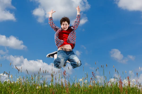 Boy jumping against blue sky — Stock Photo, Image