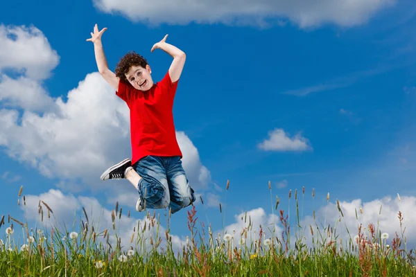 Junge springt gegen blauen Himmel — Stockfoto