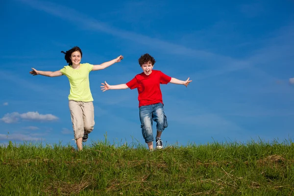 Chica y niño saltando, corriendo al aire libre — Foto de Stock