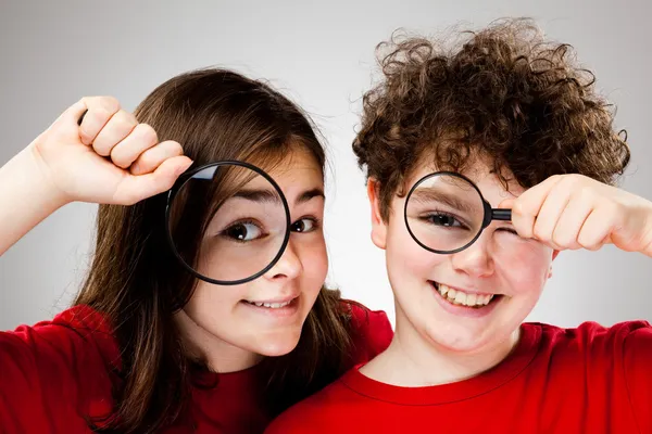 Kids holding magnifying glasses Royalty Free Stock Photos