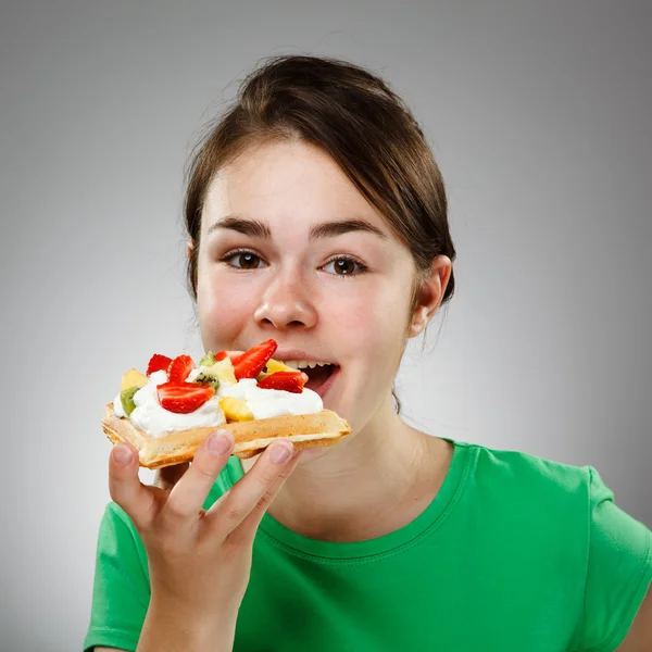 Girl eating cake with cream and fruits — Stock Photo, Image