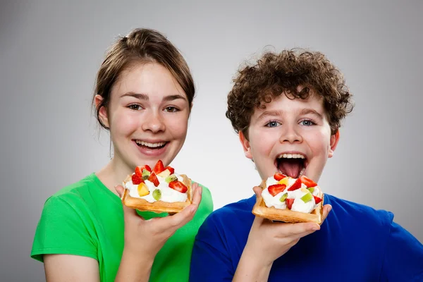 Kinder essen Kuchen mit Sahne und Früchten — Stockfoto