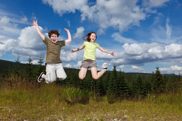 Chica y niño saltando, corriendo al aire libre — Foto de Stock