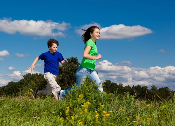 Ragazza e ragazzo saltare, correre all'aperto — Foto Stock