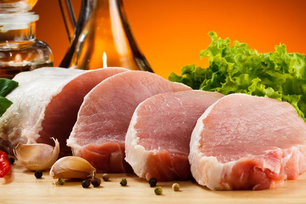 Rohes Schweinefleisch auf Schneidebrett und Gemüse — Stockfoto