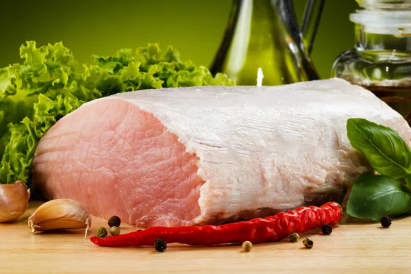 Rauw varkensvlees op snijplank en groenten — Stockfoto