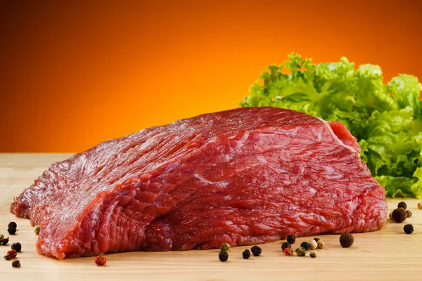 Carne crua sobre tábua de corte e pimenta preta — Fotografia de Stock