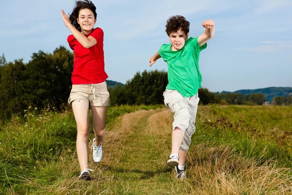 Ragazza e ragazzo saltare, correre all'aperto — Foto Stock