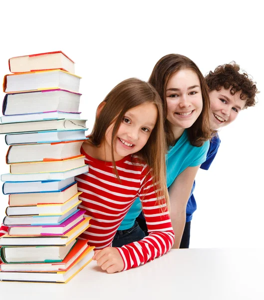 Estudantes espreitando atrás de pilha de livros — Fotografia de Stock