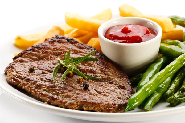 Gegrilde steaks, gebakken aardappelen en groenten — Stockfoto