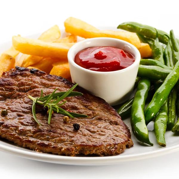 Gegrilde steaks, gebakken aardappelen en groenten — Stockfoto