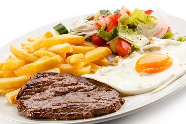 Bifes grelhados, batatas fritas, ovo frito e legumes — Fotografia de Stock