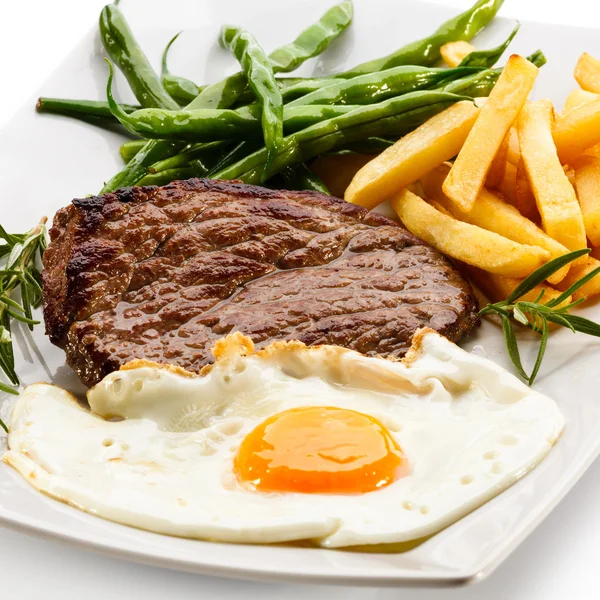 Grilované steaky, hranolky, smažená vejce a zelenina — Stock fotografie