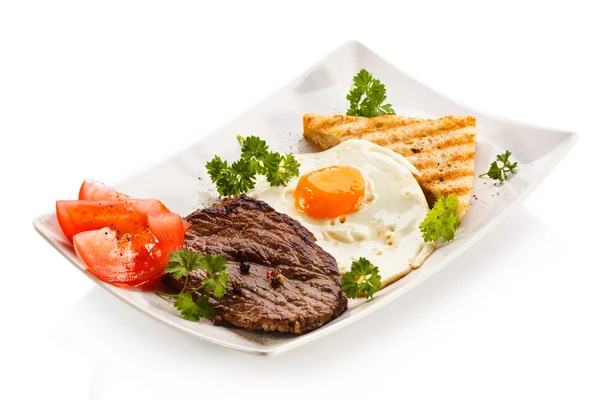 Izgara biftek, patates kızartması, kızarmış yumurta ve sebze. — Stok fotoğraf
