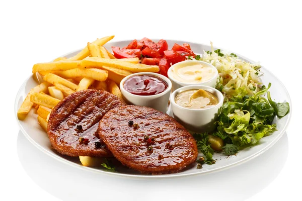 Grilled steaks, French fries and vegetables — Stock Photo, Image