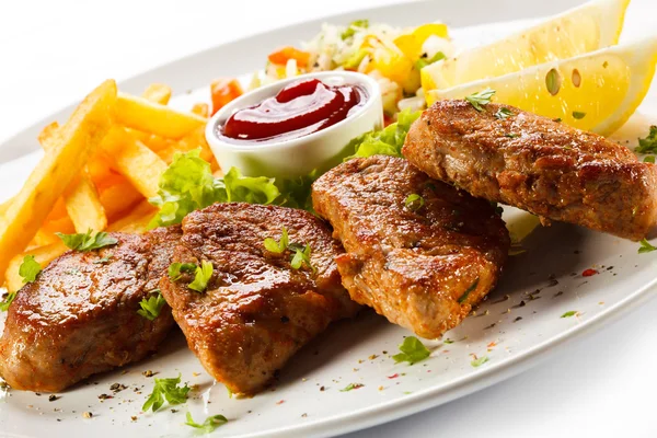 Grilled steaks, French fries and vegetables — Stock Photo, Image