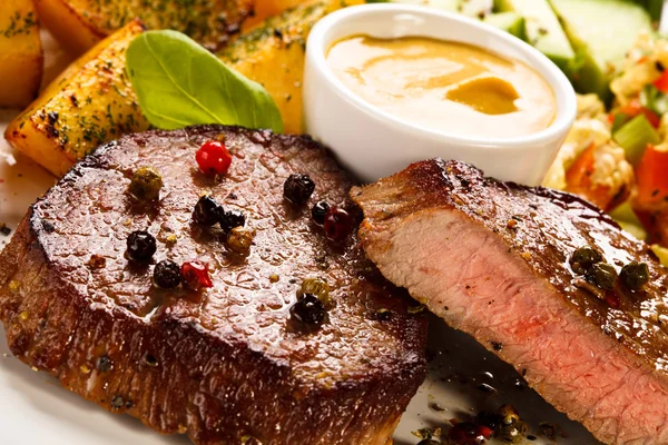 Grilled steaks, baked potatoes and vegetable salad — Stock Photo, Image