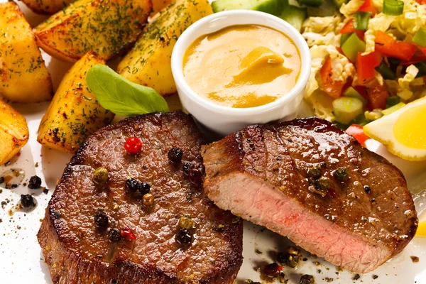 Gegrilde steaks, gebakken aardappelen en groentesalade — Stockfoto