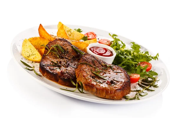 Steaks grillés, pommes de terre cuites au four et salade de légumes — Photo
