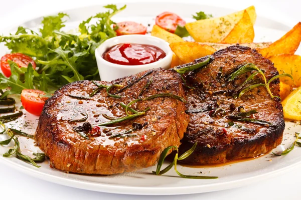 Grilled steaks, baked potatoes and vegetable salad — Stock Photo, Image