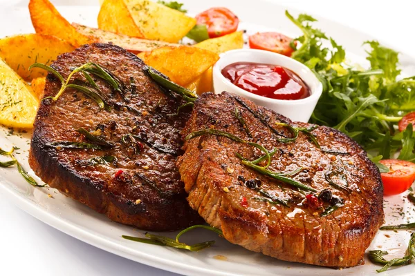 Steaks grillés, pommes de terre cuites au four et salade de légumes — Photo