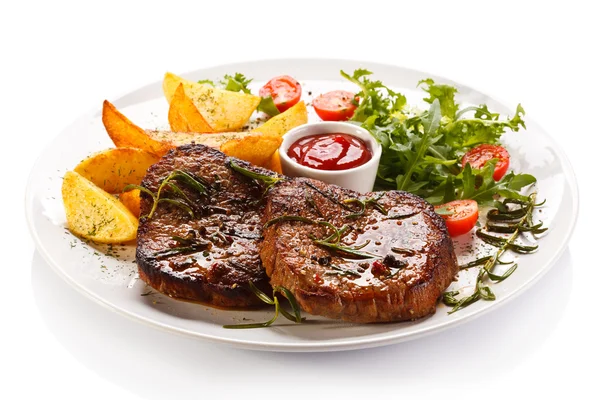 Gegrillte Steaks, Bratkartoffeln und Gemüsesalat lizenzfreie Stockbilder