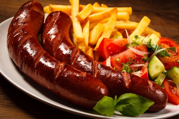 Salsichas grelhadas com batatas fritas e legumes — Fotografia de Stock