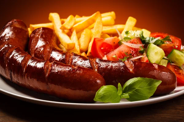 Salsichas grelhadas com batatas fritas e legumes — Fotografia de Stock