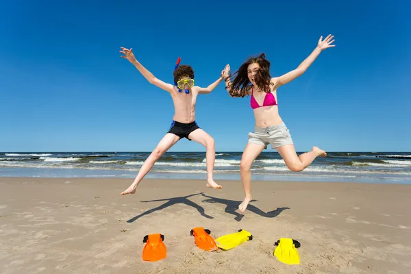 Teenage girl and boy jumping, running on beach — Stock Photo, Image