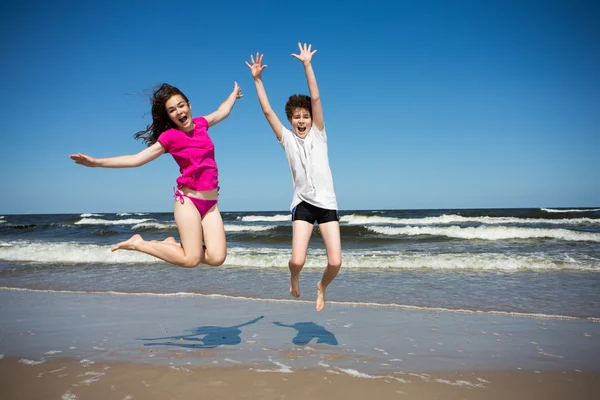 Menina e menino pulando juntos — Fotografia de Stock