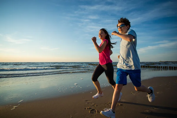 Mädchen und Junge im Teenager-Alter rennen am Strand — Stockfoto