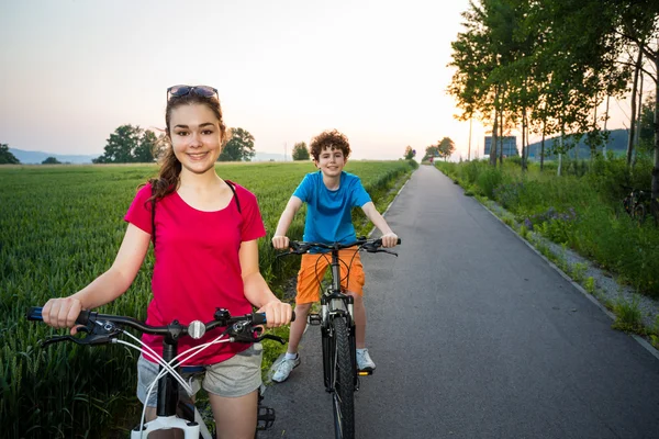 Ragazza adolescente e ragazzo in sella alle bici — Foto Stock