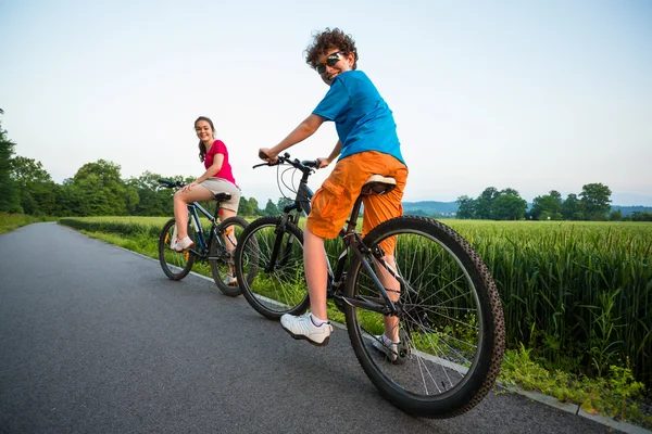 Tiener meisje en jongen paardrijden fietsen — Stockfoto