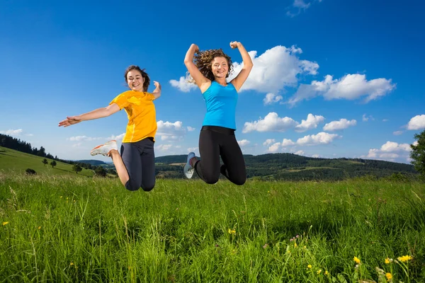 Dos mujeres saltando al aire libre — Foto de Stock