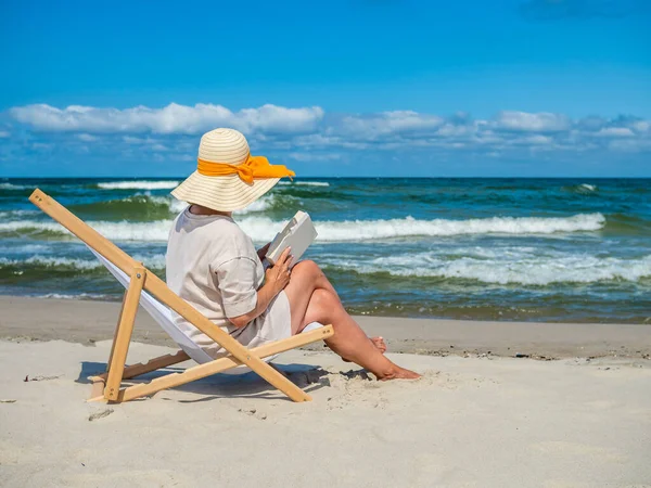 女人坐在沙滩上躺在日光浴床上休息 — 图库照片