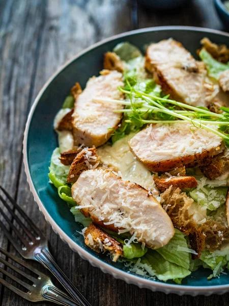 シーザーサラダ 木製のテーブルの上に揚げ鶏の胸肉と野菜 — ストック写真