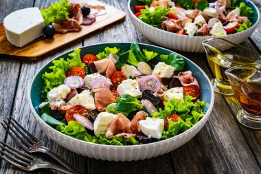 Tasty salad - prosciutto di Parma, feta cheese and fresh, green vegetables on wooden table clipart