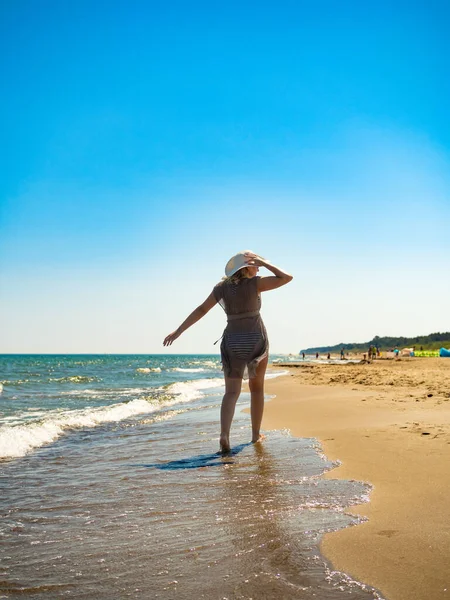 太陽が降り注ぐビーチの上を歩く女性 — ストック写真