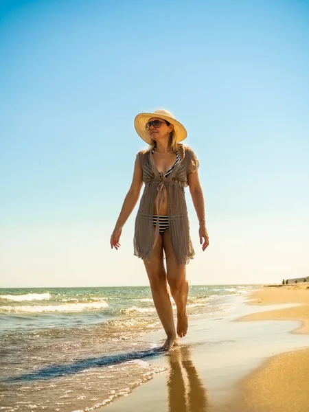 太陽が降り注ぐビーチの上を歩く女性 — ストック写真